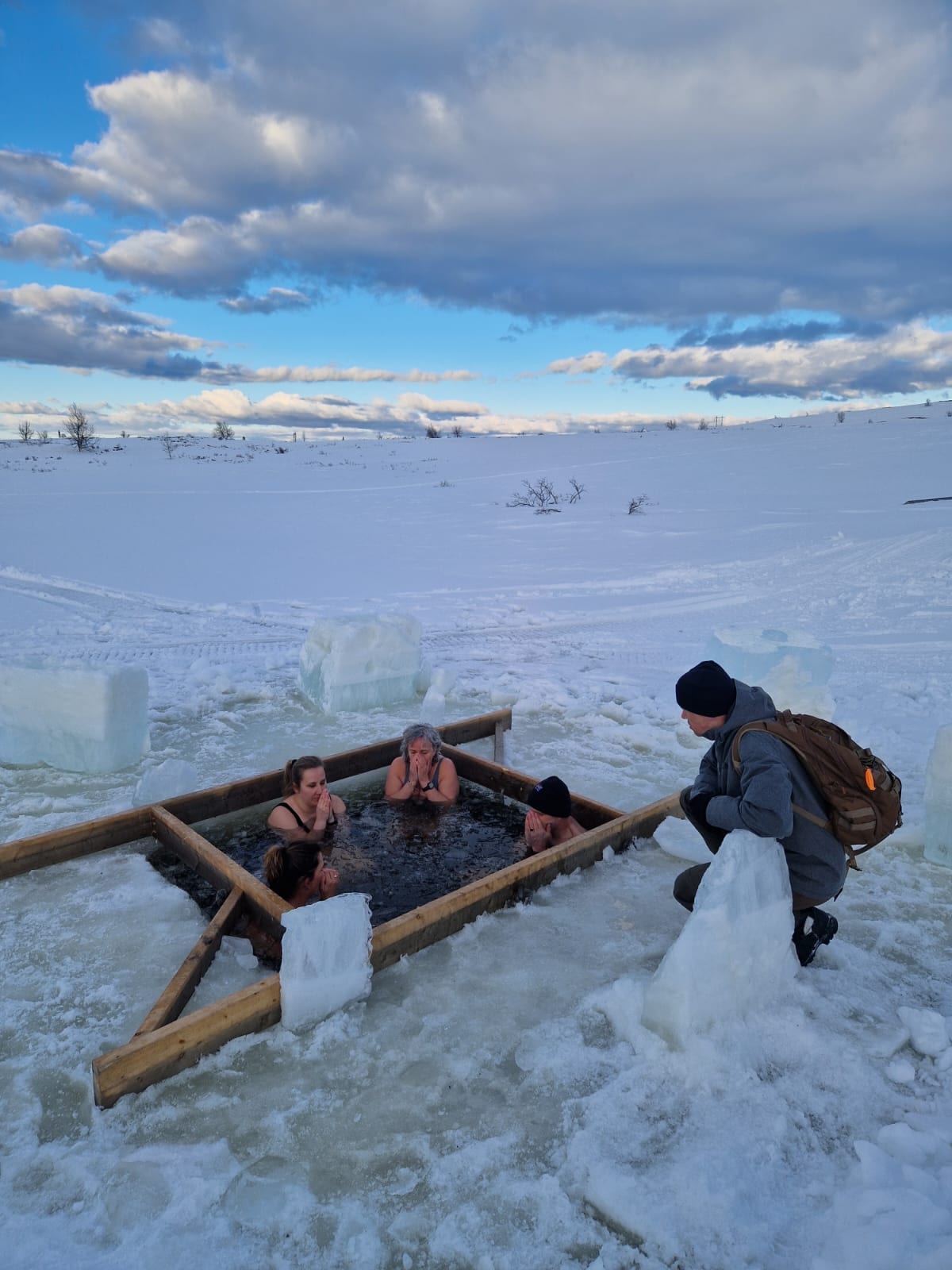 Group in an ice bath at blue hour in Norway, surrounded by snow